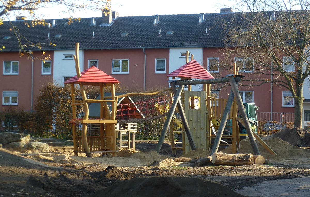 Spielplatz Wacholderweg mit hölzernen Spieltürmen und Seilbrücke, Aufnahme von 2019